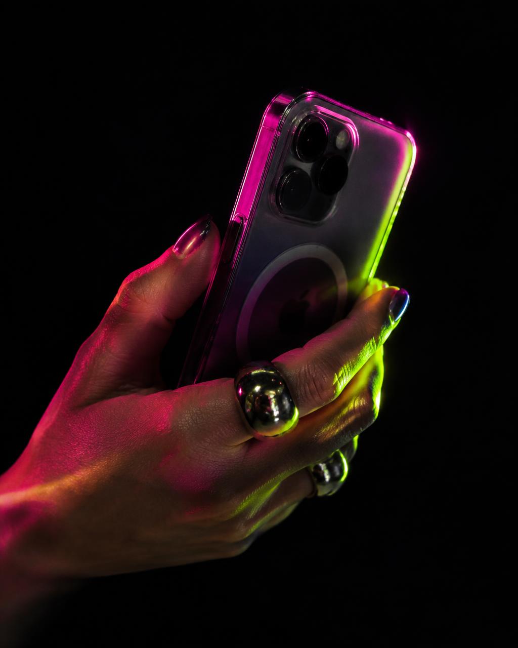 A hand holding a phone glowing pink and lime